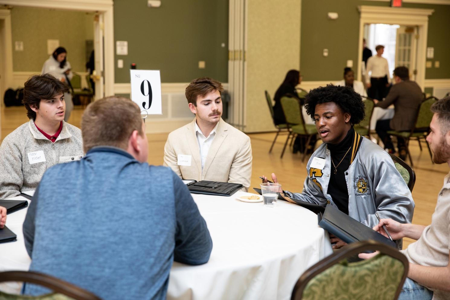 Business students interviewing a business professional in a roundtable setting.