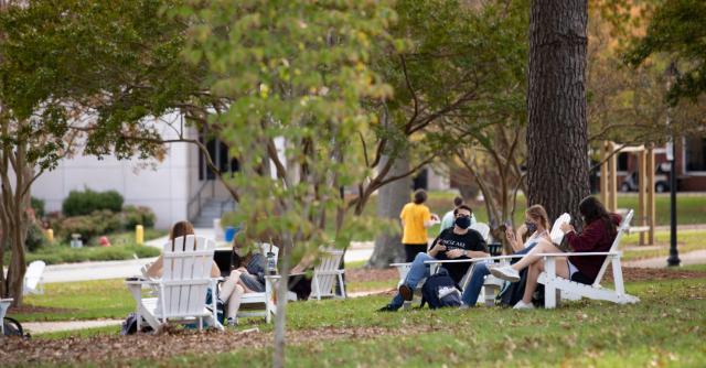 Students sitting on Stubbs Mall in Adirondack chairs